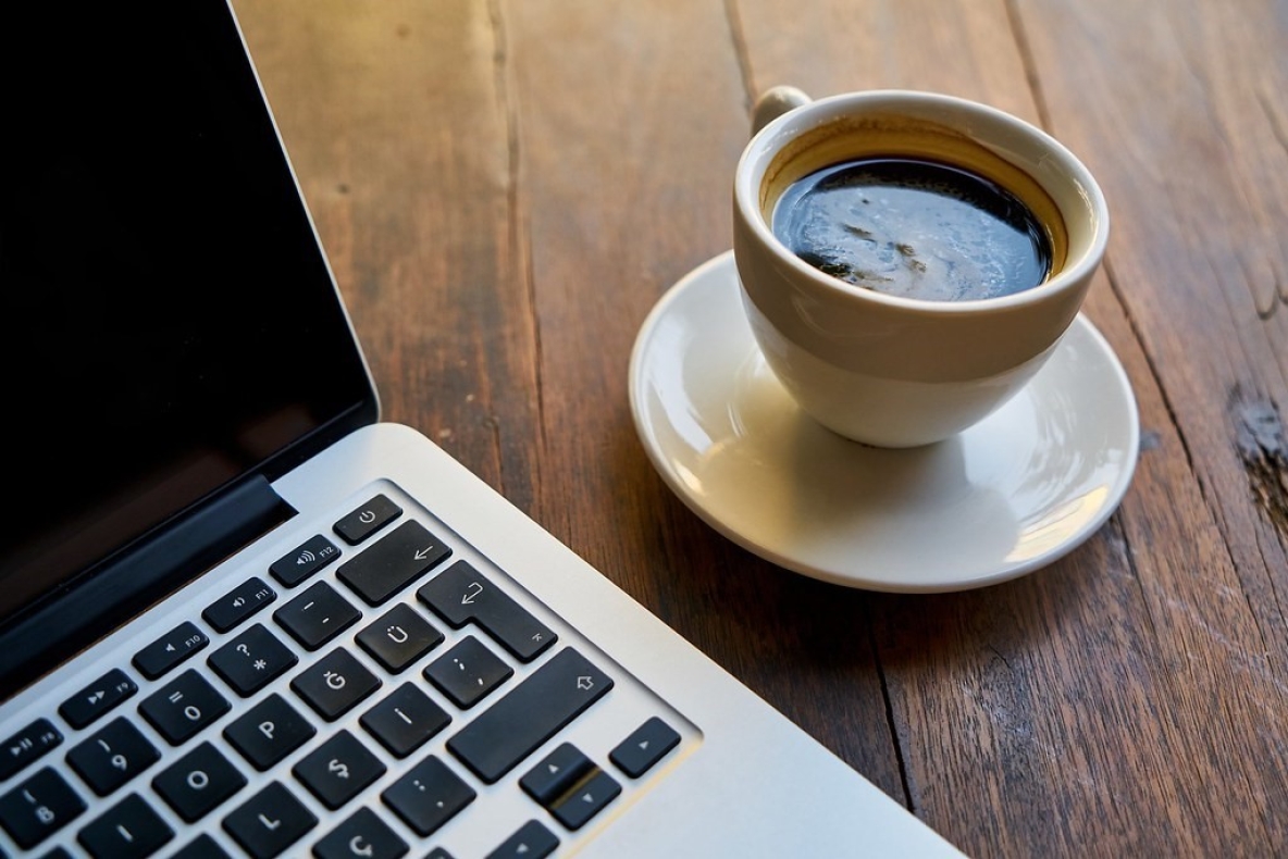 Image shows a cup of coffee and a laptop 