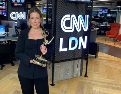 A woman with blonde hair in a black suit holding an Emmy Award in CNN's London office